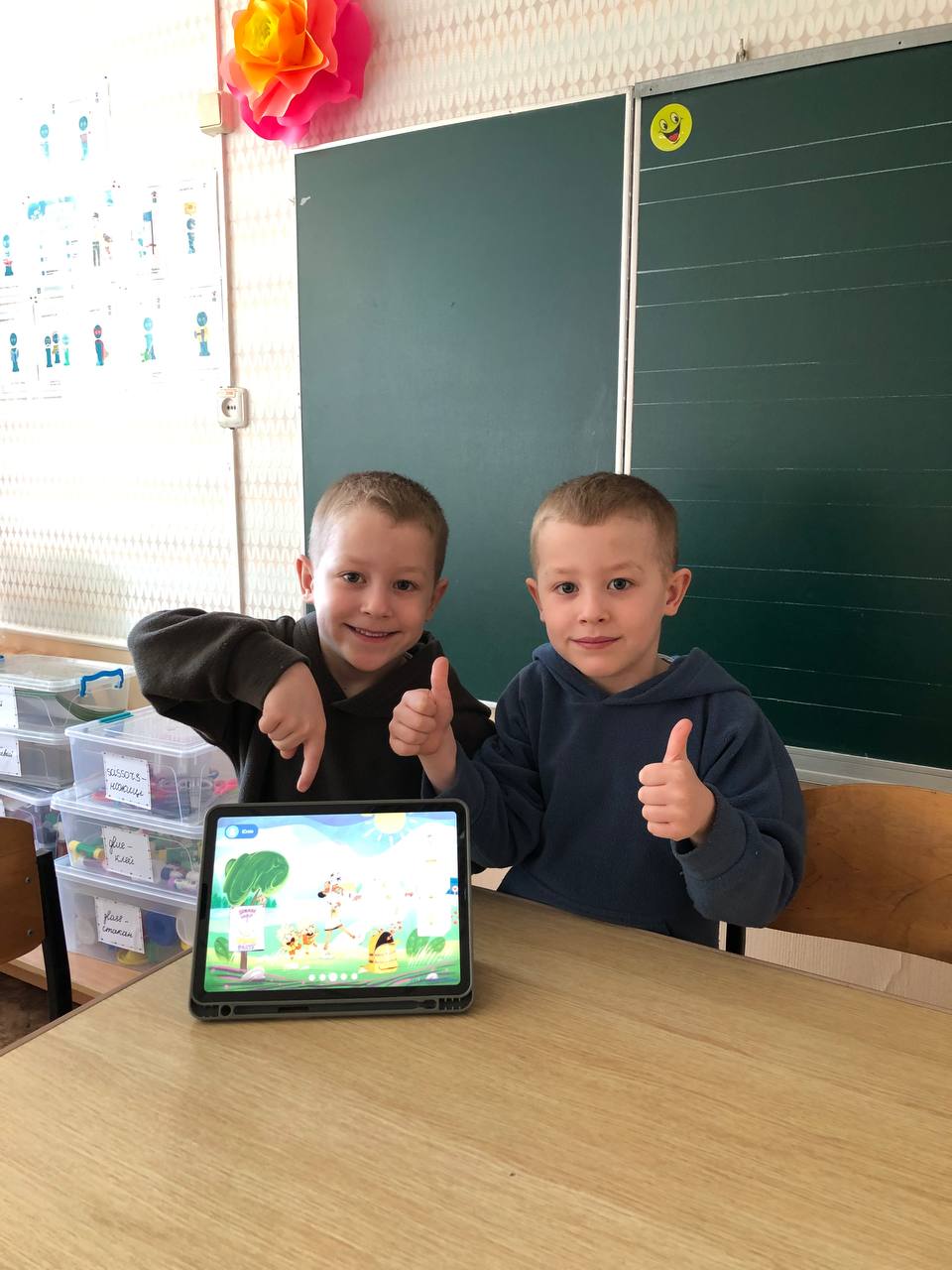 Two children with a tablet in a classroom